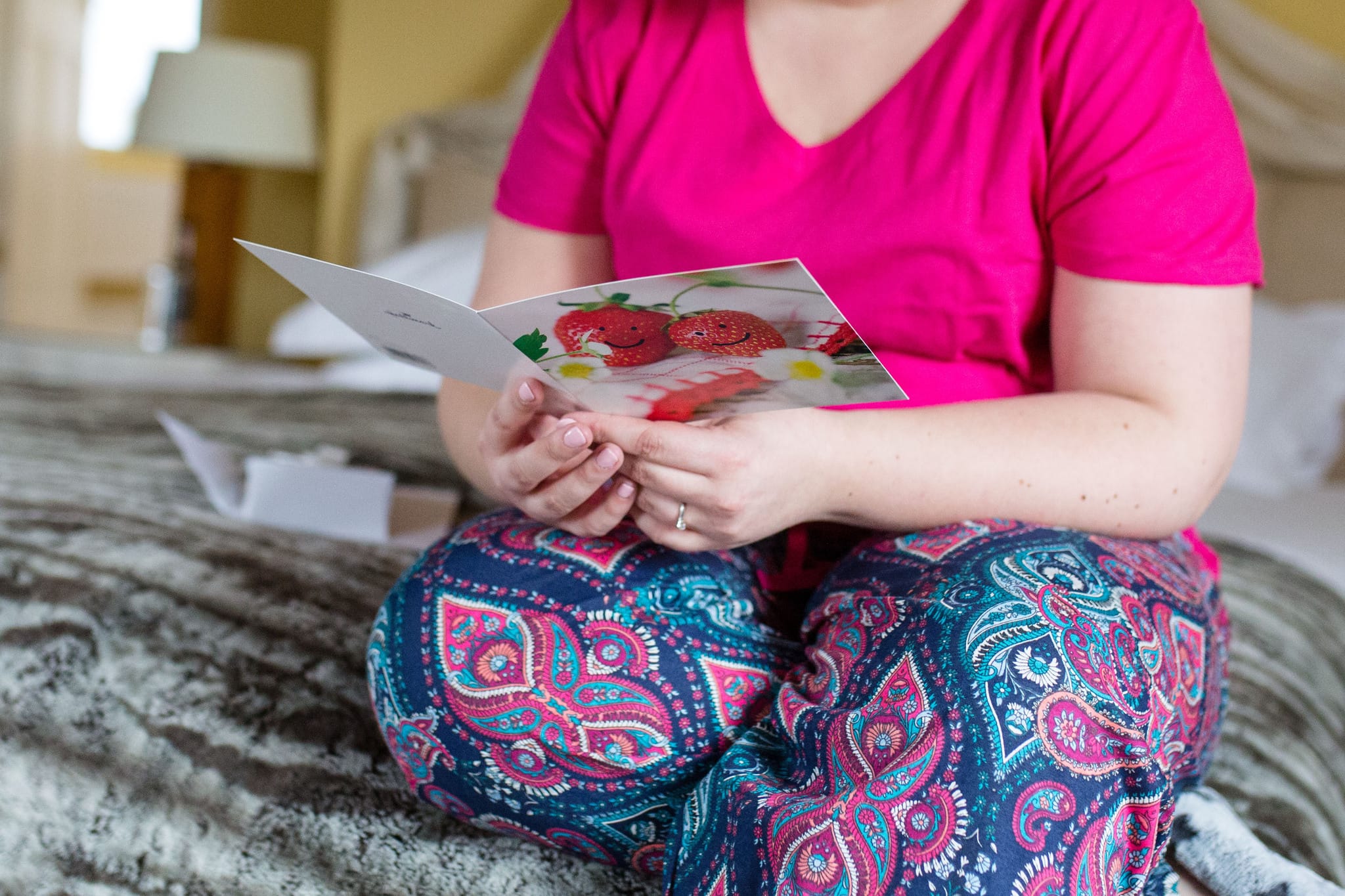 Bride in colourful pyjamas reading card with strawberries on the front