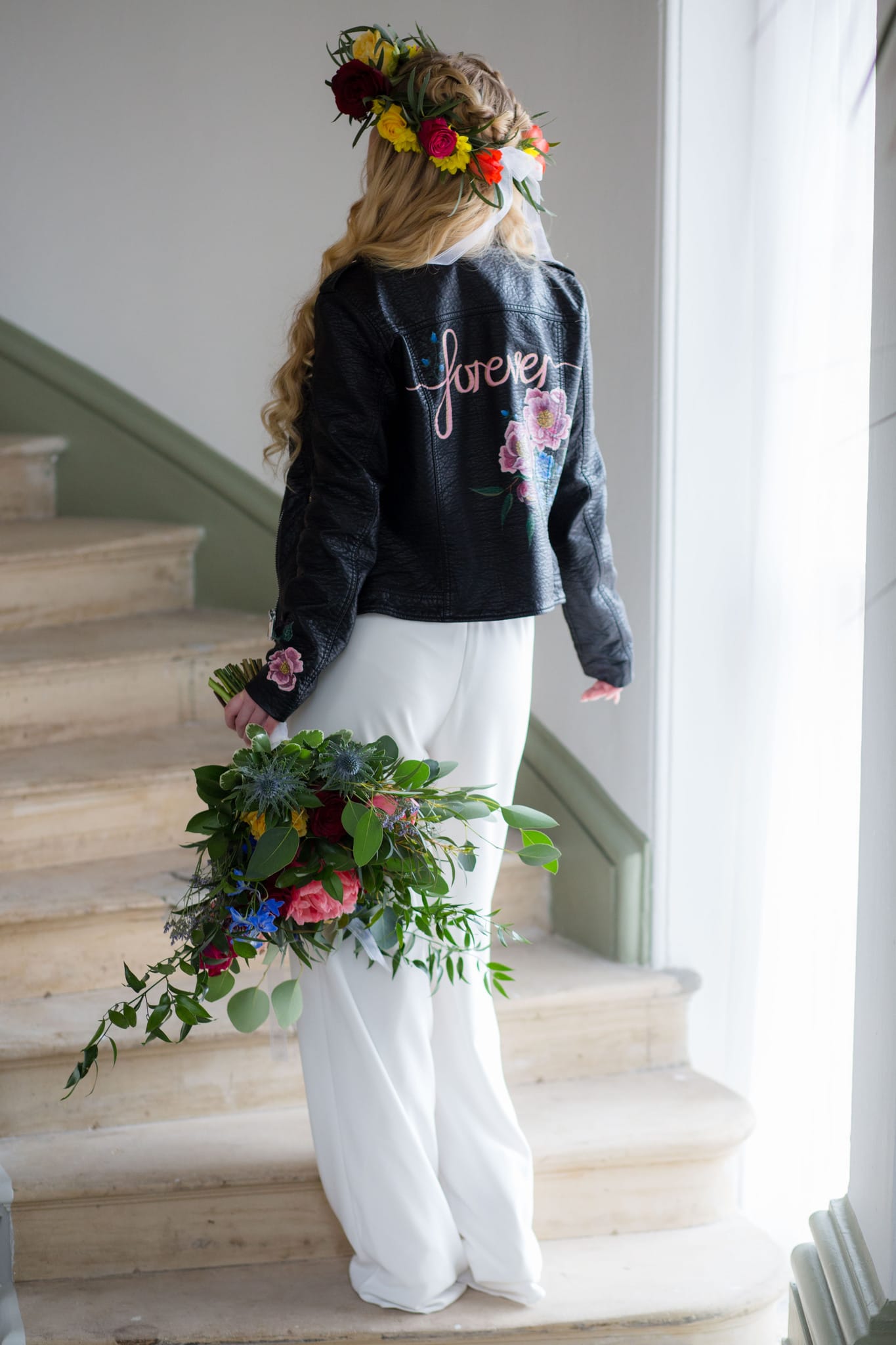 Boho Bride wearing flower crown and leather jacket and bridal jumpsuit