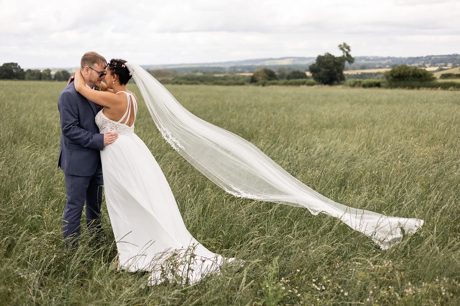 High Grosvenor Hotel wedding photographer Nicola Gough Couple in green field on wedding day with veil blowing in wind