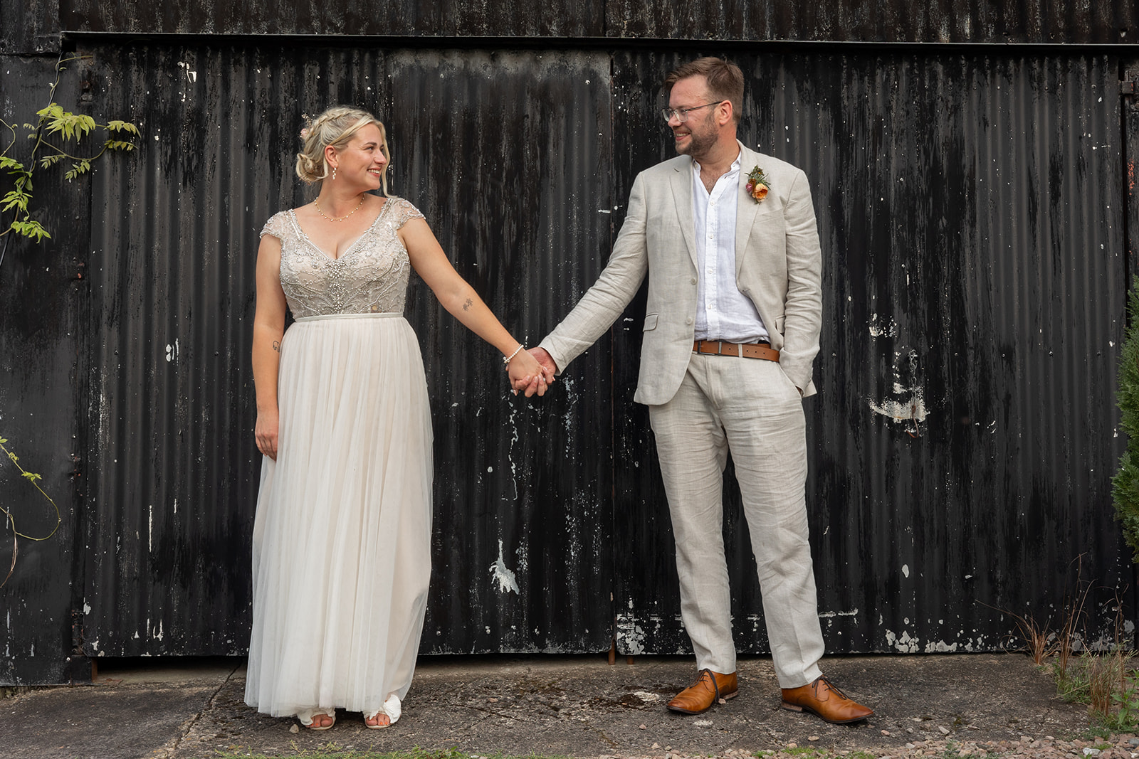 Couple holding hands in front of black barn