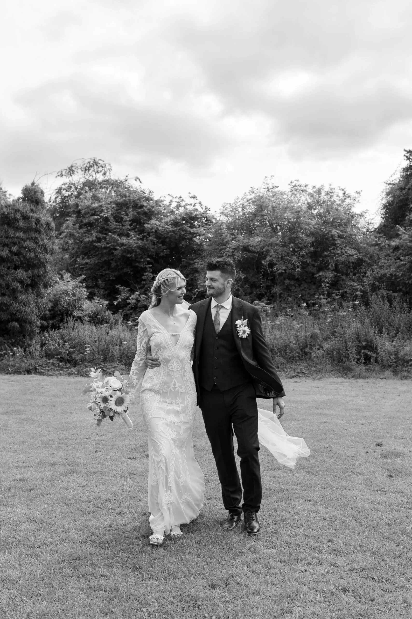 Black and white image showing couple walking on their wedding day