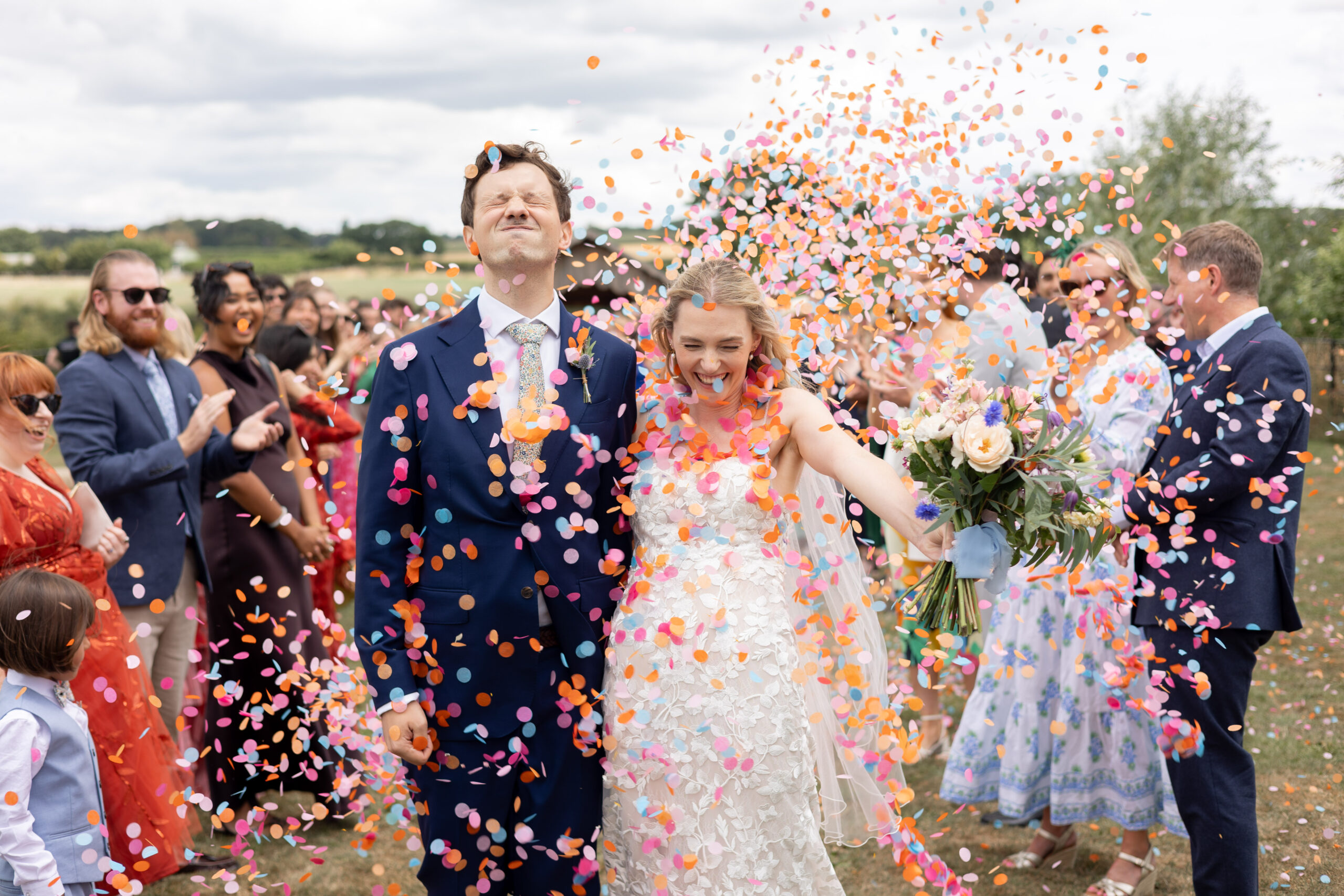 A couple on their wedding day are showered with colourful confetti as they walk down the aisle