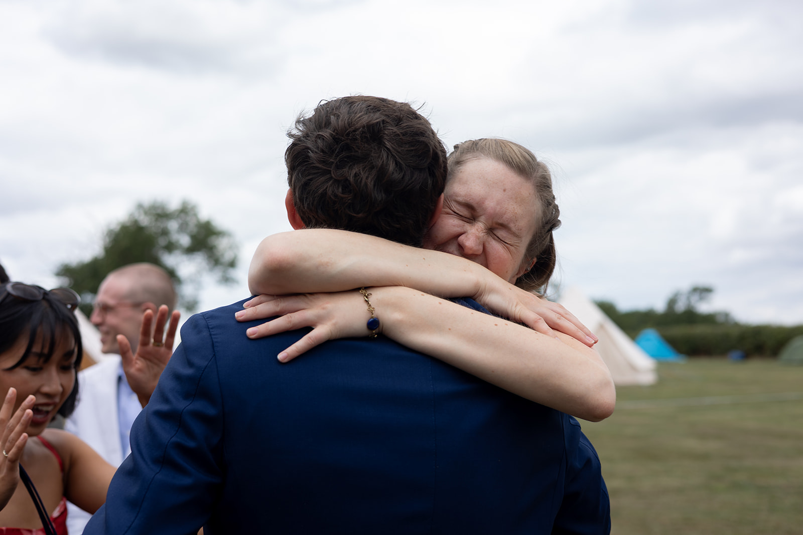 Stanford Farm wedding photographer a young woman hugs a young man tightly, she has her eyes shut, his back is to the camera